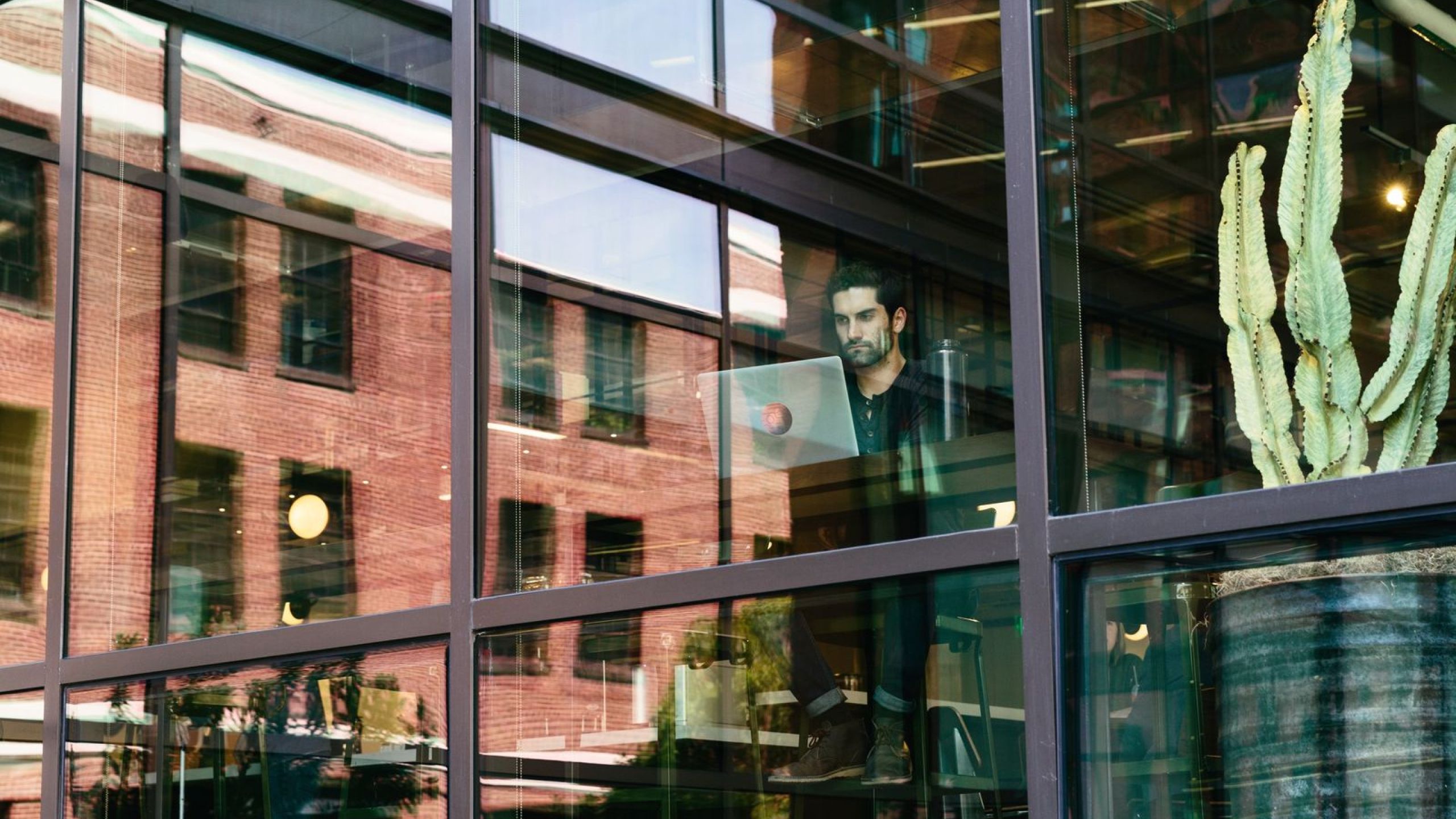 A man with an open laptop in his hands standing in front of an office