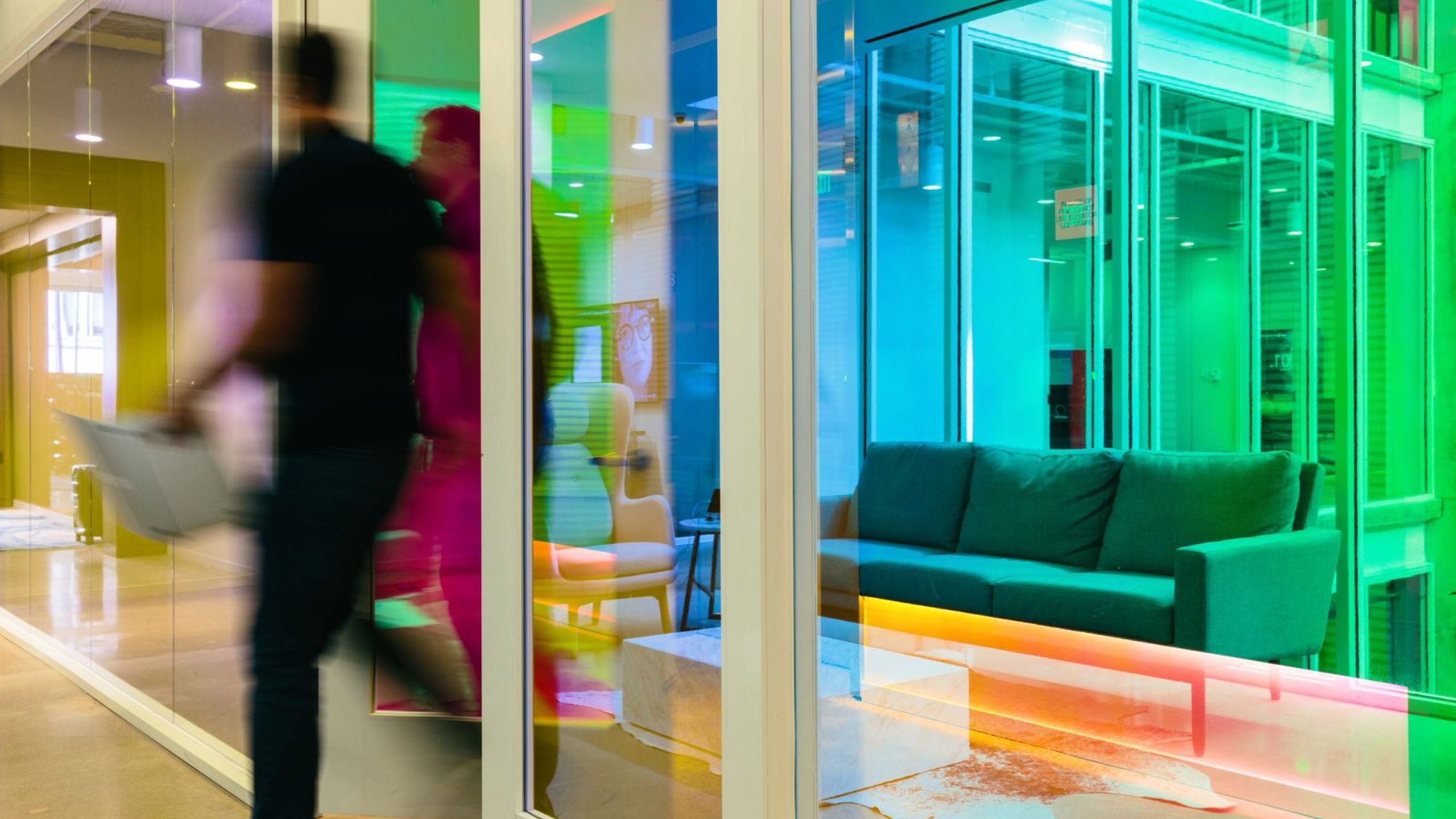 A man with a laptop running through an office hallway