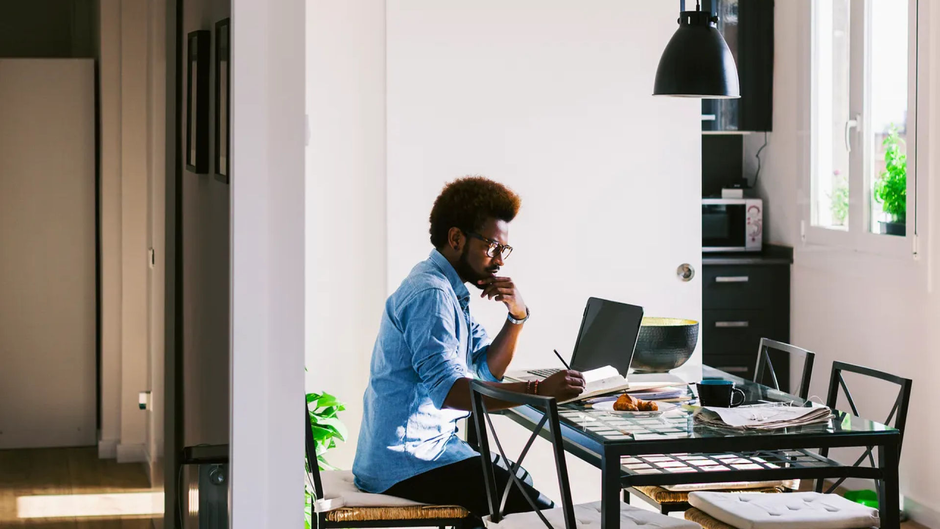 Person working at a table with a laptop and notebook, in a home setting, representing an effective work-from-home setup.